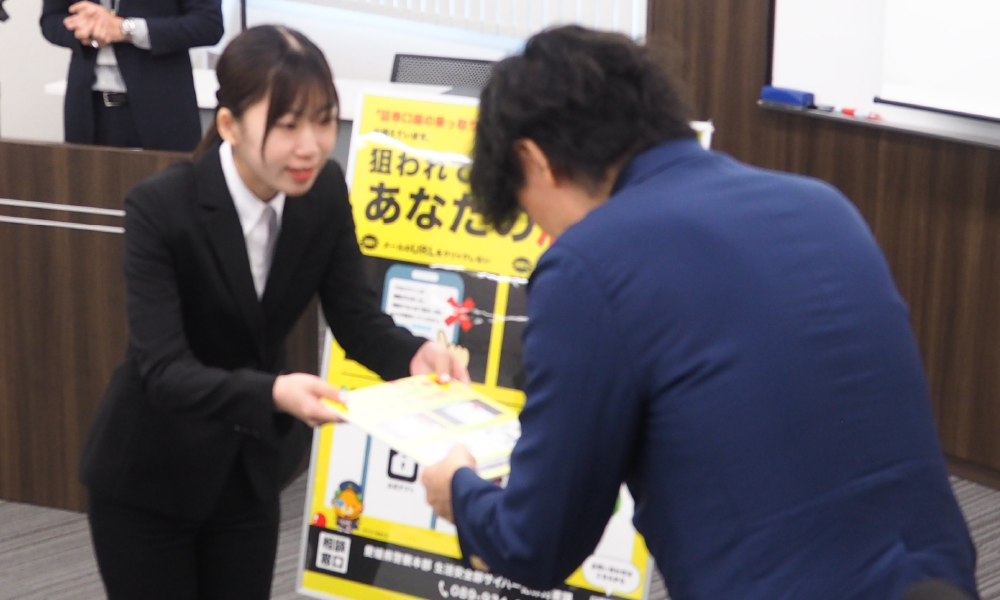 証券口座乗っ取り防止ポスターを渡している写真